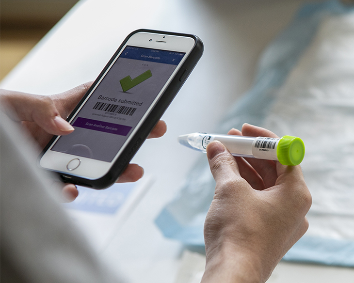 A Duke student is using a cellphone app to scan a vial of saline solution provided in the COVID self-testing kit.
