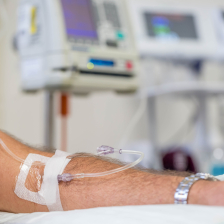 A person rests their arm on a treatment chair as immunotherapy drugs are administered via an IV.
