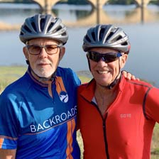 two men smiling with bicycle helmets