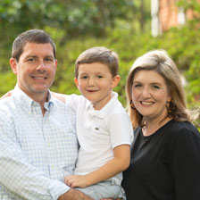 father holding son with mother standing beside them