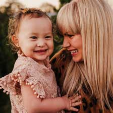 mother holding daughter and smiling