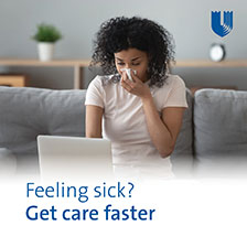 woman at the computer with a tissue to her nose