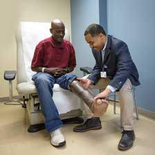 Bruce DeShazo sits on a chair as Malcolm DeBaun, MD looks at his leg