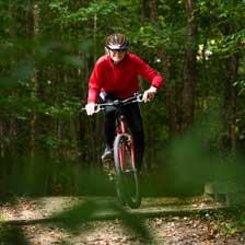 Harlin riding his bike in the woods with a red shirt on