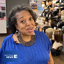 Woman standing in boutique featuring wigs