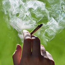 Hand holding smoldering cigarette