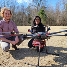 Dr. Monique Starks poses with a colleague and a drone carrying an AED