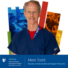 Todd smiling in blue scrubs with a colorful Duke Health shield behind him. 