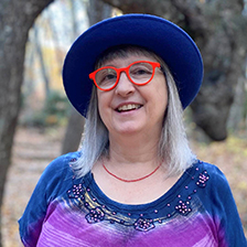 Beth Huber stands in front of a tree smiling