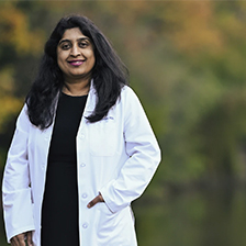 Dr. Padma Gulur standing by a tree lined background