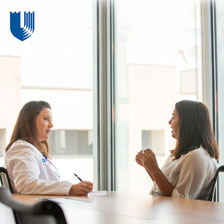 Susannah White speaking with a patient at a table