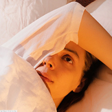 Woman in bed with covers over one quarter of face