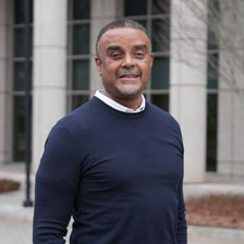 Derek Hill stands outside and smiles at the camera