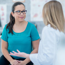 a woman sits in a chair listening to the doctor