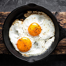 Eggs in a skillet on a wooden plank