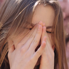 Woman rubs eyes from allergies
