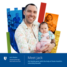 Jack holds his infant daughter with a colorful Duke Health shield in the background. 