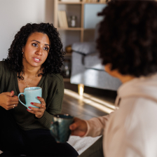 Women discuss a topic while sharing cups of coffee