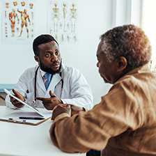 a doctor sits at a table with a patient and talks to him