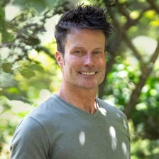 David stands outside in his garden smiling