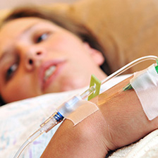 woman lies on a hospital bed with an iv