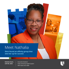 Nathalia smiles in glasses and an orange suit with a colorful Duke shield in the background.