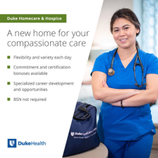 Female nursing team member smiles in blue scrubs with a Duke HomeCare & Hospice bag beside her.