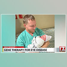Man holds baby in a clinical setting.