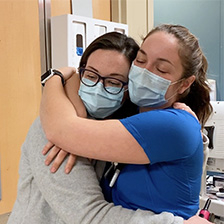 Health Care Workers hug in a clinical setting