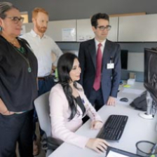 a panel of doctors stands and looks at a computer