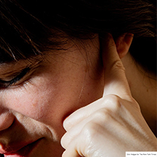 Person holds finger in ear trying to pop ear for travel. NYT Photo Credit.