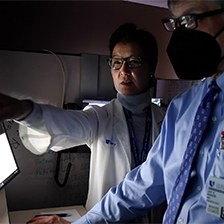 Doctor points at computer screen while a colleague looks on
