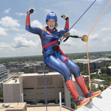A woman in a Captain Marvel costume perches on the ledge of Duke Central Tower on the Duke Health Campus in Durham