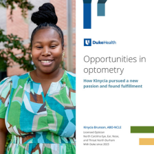 Kinycia smiles in a green and blue patterned dress outside the Duke facility where she works.