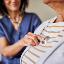 A doctor holds a stethescope to a woman's chest