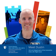 Dustin smiles in a blue Duke Life Flight jumpsuit. There is a colorful Duke Health shield behind him.