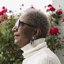 Josie smiles in front of a rose bush, looking off into the distance.