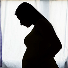 Pregnant woman stands in silhouette