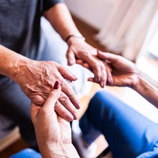 A doctor holds the hands of a patient