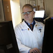 Chuck Scales, M.D. works between two computer monitors in a laboratory setting