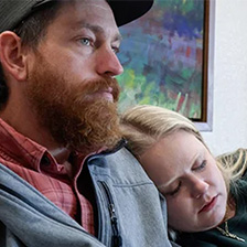 A man and woman hug in a hospital waiting room.