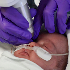 A clinician examines a baby's eye with a scope device