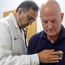 Doctor Manesh Patel examining a patient in a room using a stethoscope